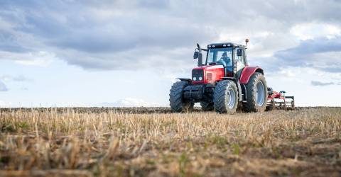 Rode tractor dat op het land aan het werk is