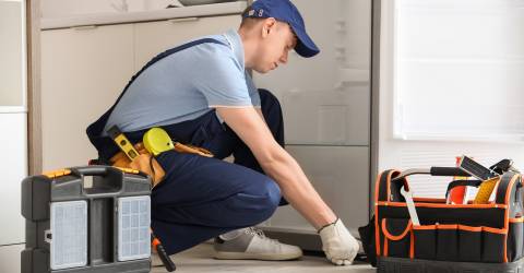 Monteur repareert koelkast in de keuken